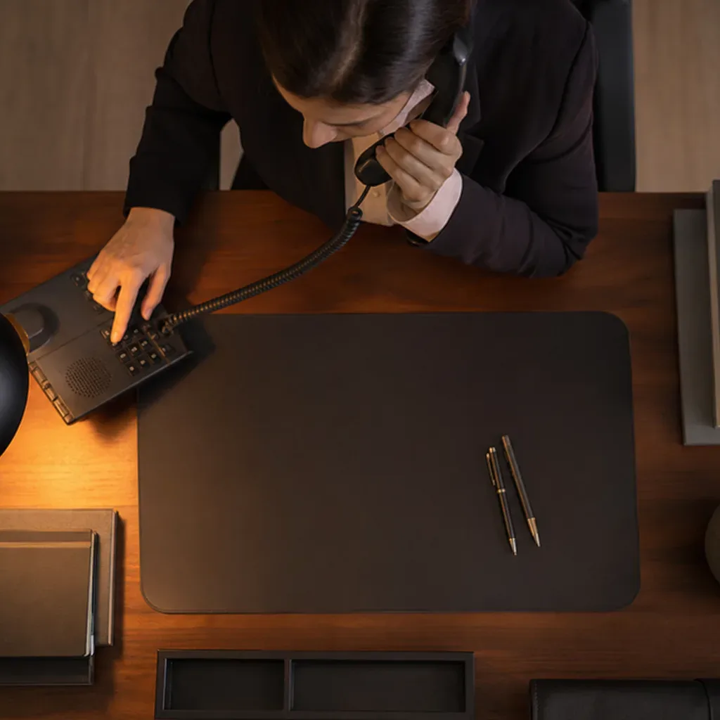 A desk phone with the handset lifted mid-call in warm lamp light