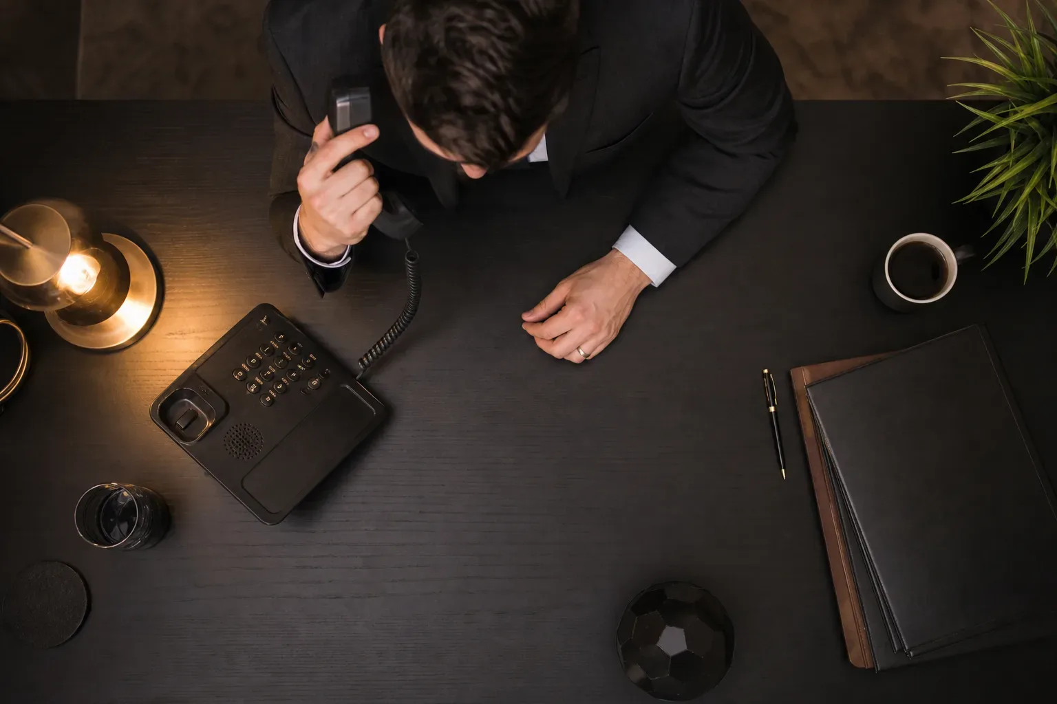 A desk phone with the handset lifted mid-call in warm lamp light