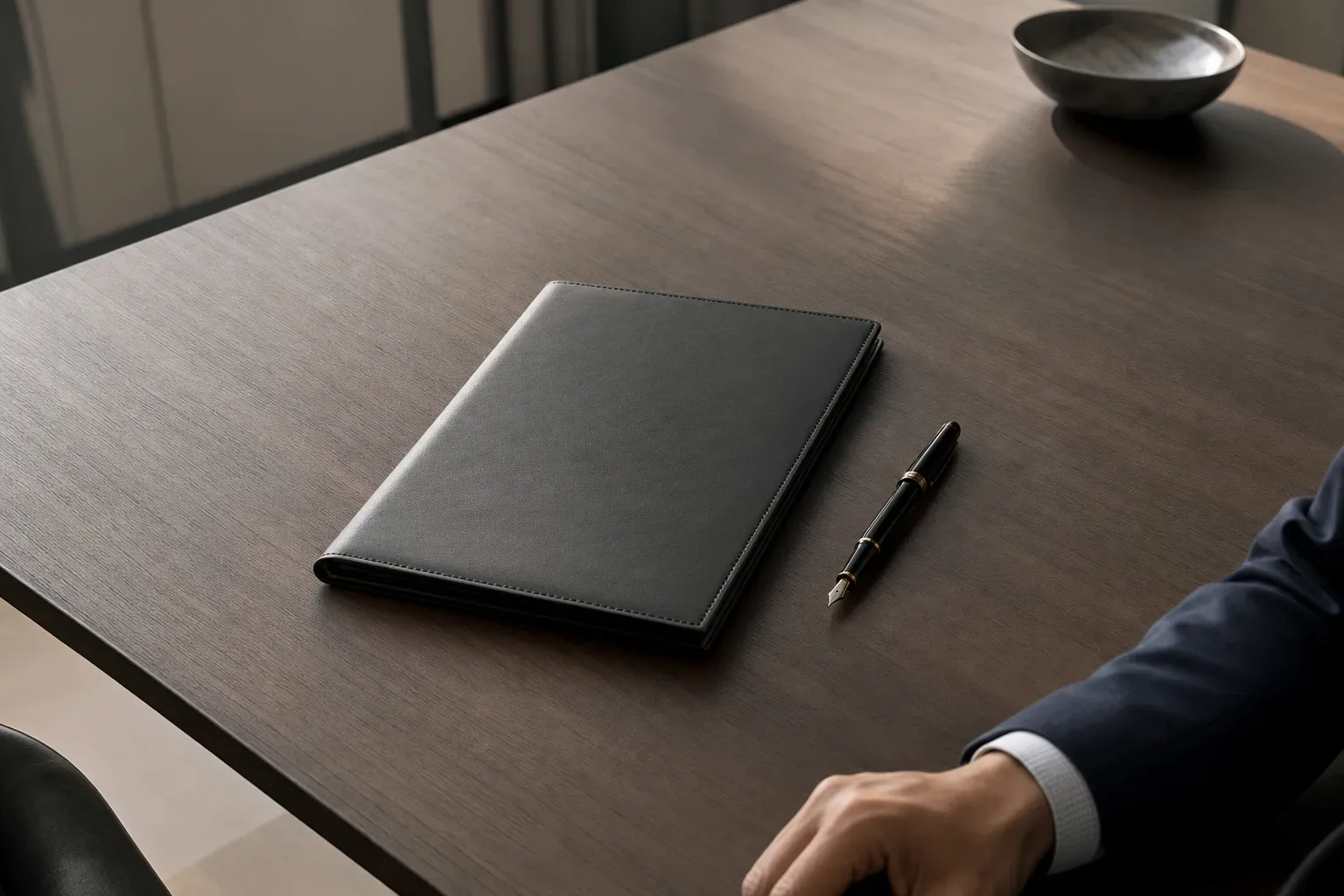 A single fountain pen laid beside a closed folder on a clean desk surface