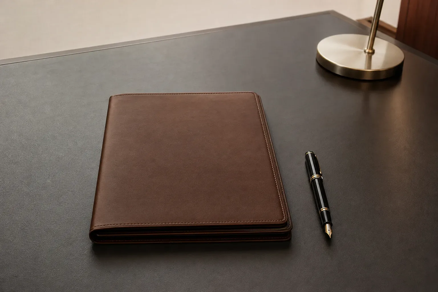 A single fountain pen laid beside a closed folder on a clean desk surface