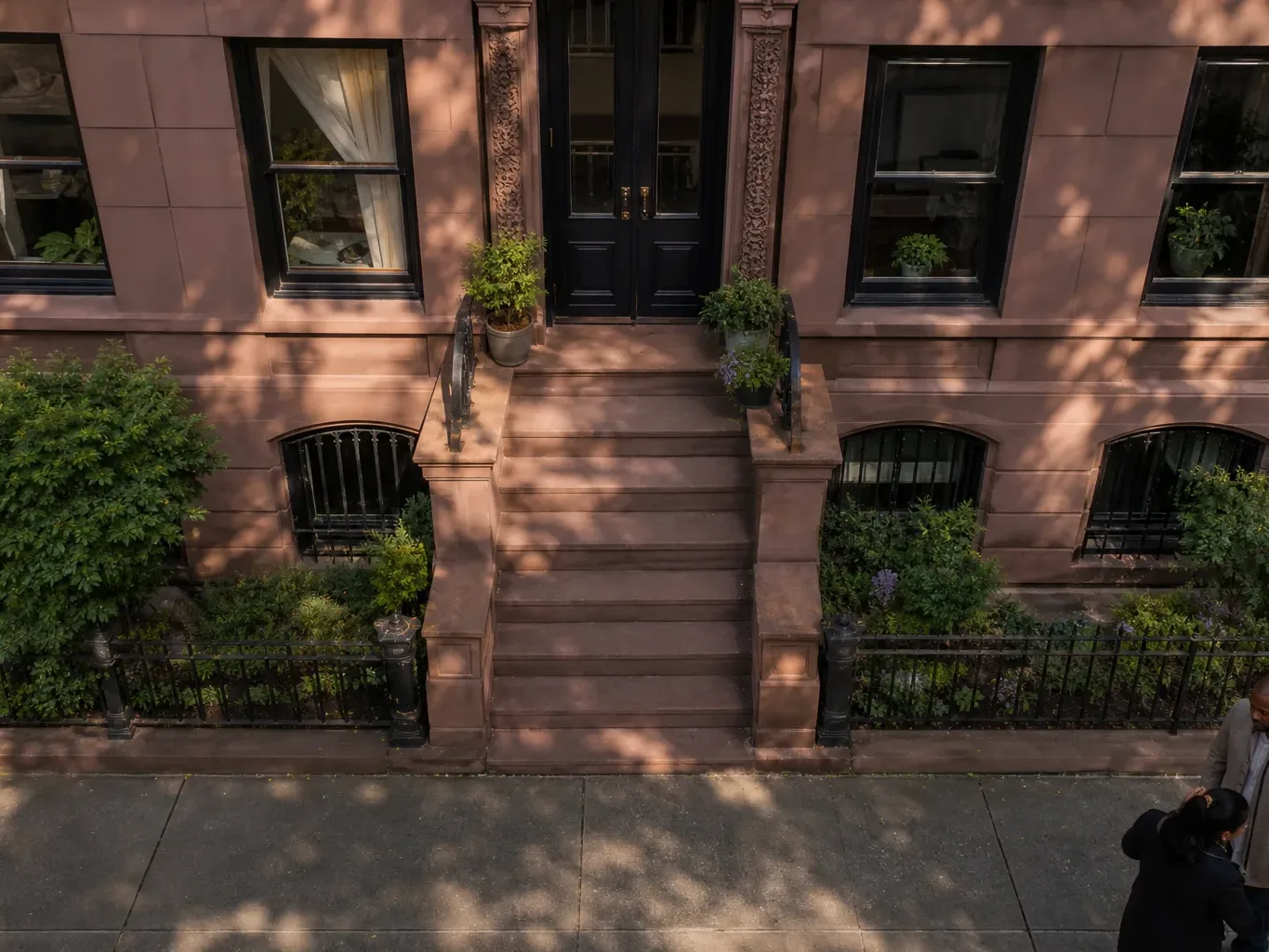 The stepped stone facade of a Brooklyn brownstone rowhouse in late afternoon light