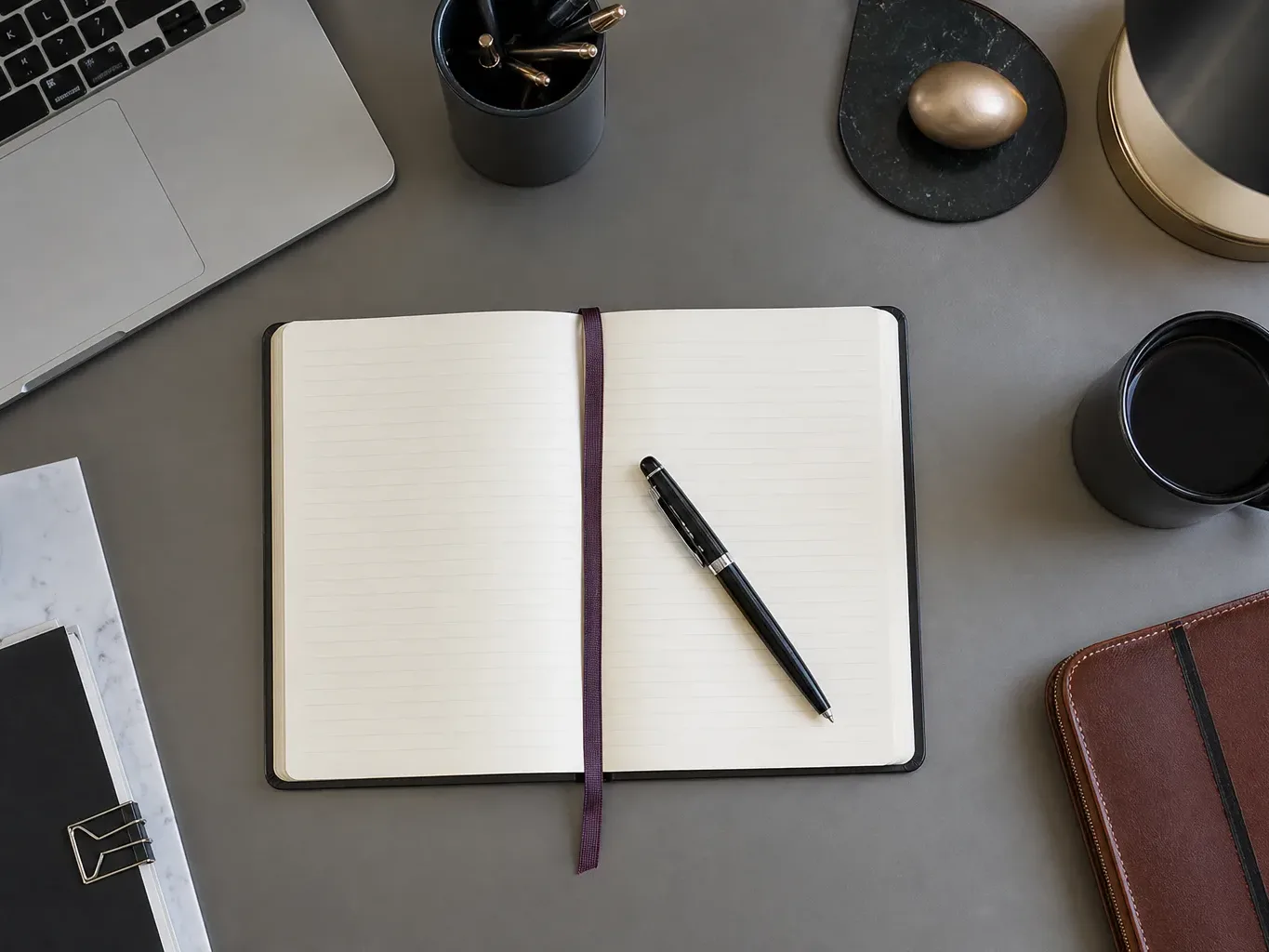 An open notebook with a pen resting across it seen from above in cool daylight