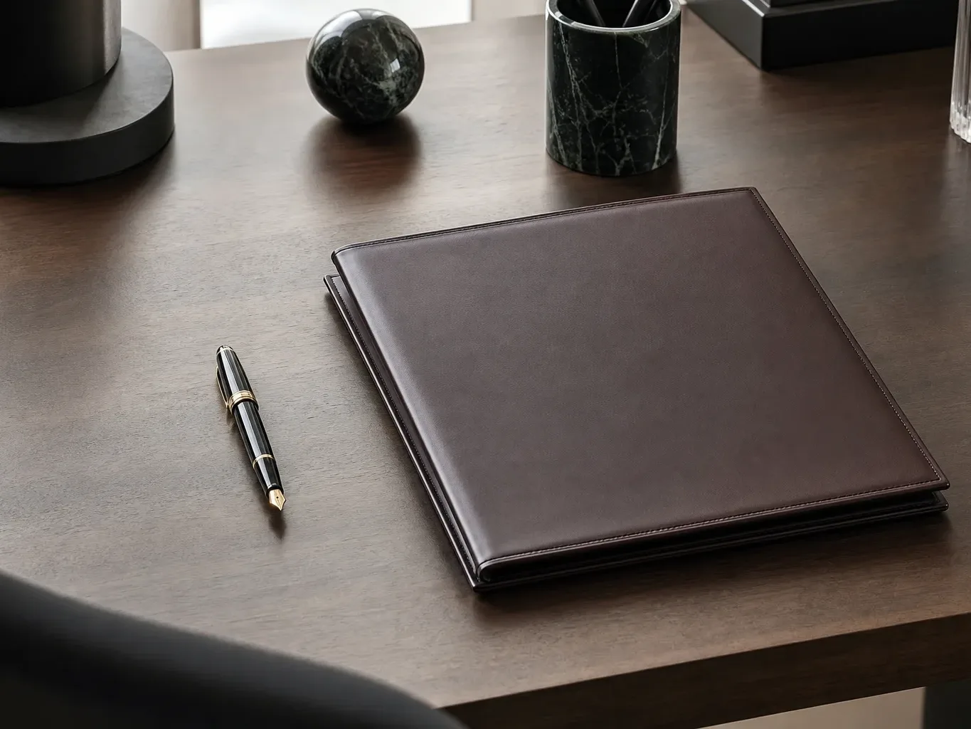 A single fountain pen laid beside a closed folder on a clean desk surface