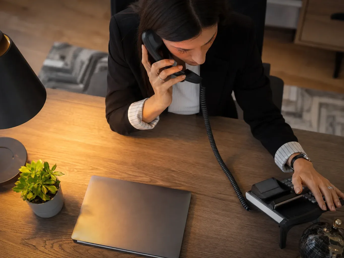 A desk phone with the handset lifted mid-call in warm lamp light